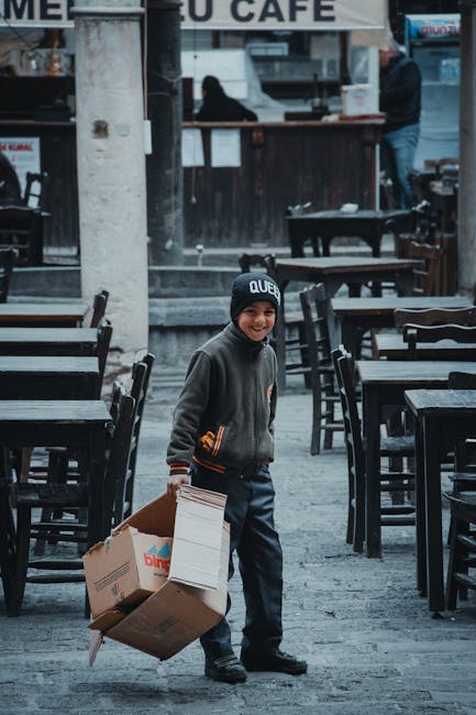 Young courier delivering a cardboard box near a cafe